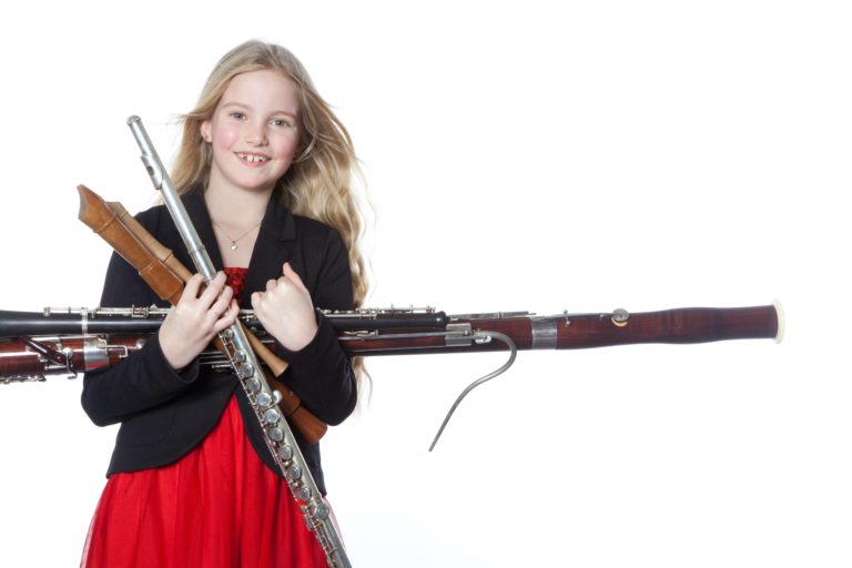 young girl holds woodwind instruments in studio