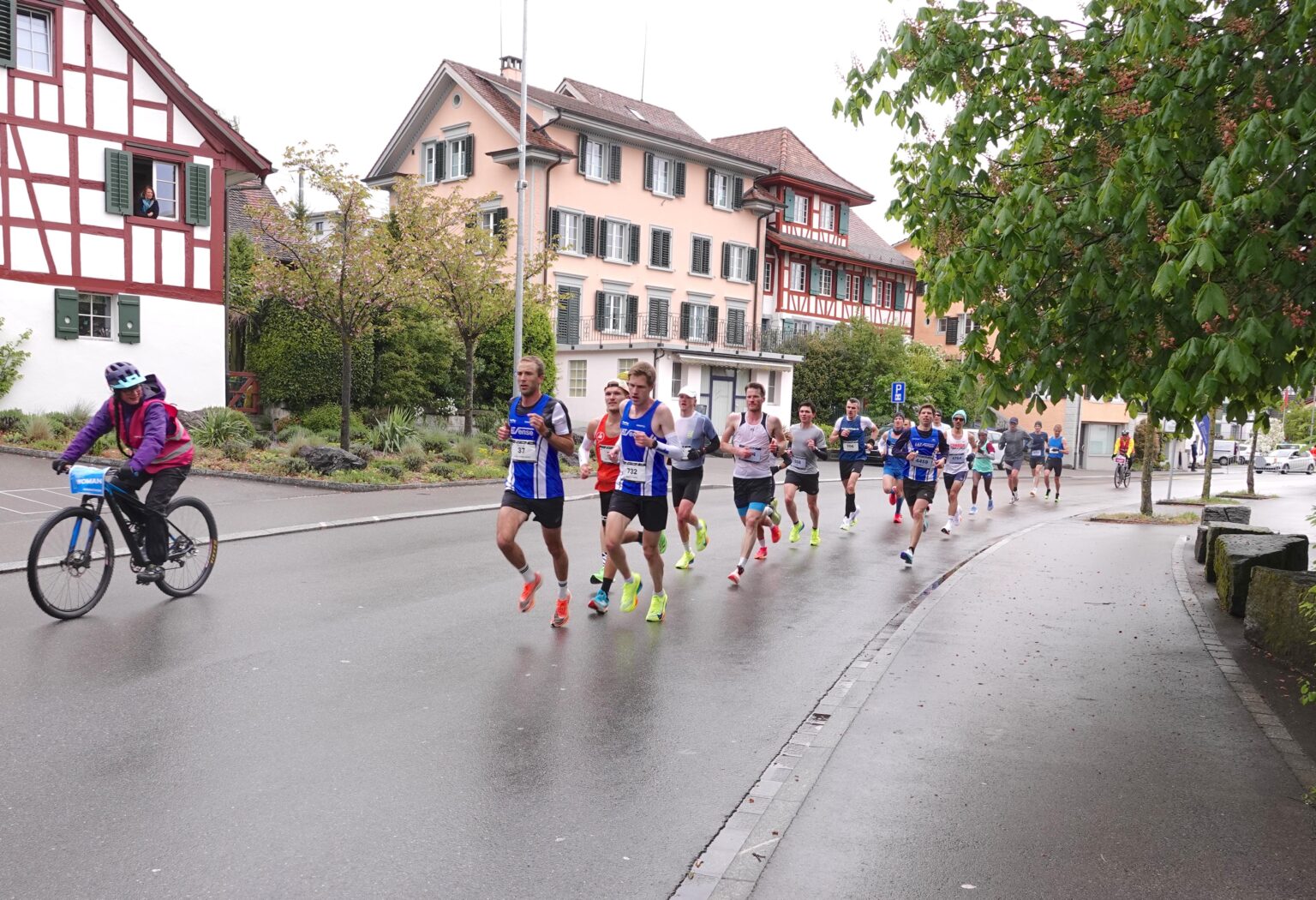 Die Läuferinnen und Läufer auf der Dorfstrasse haben die Hälfte des Marathons geschafft, nun steht der Rückweg nach Zürich bevor.
